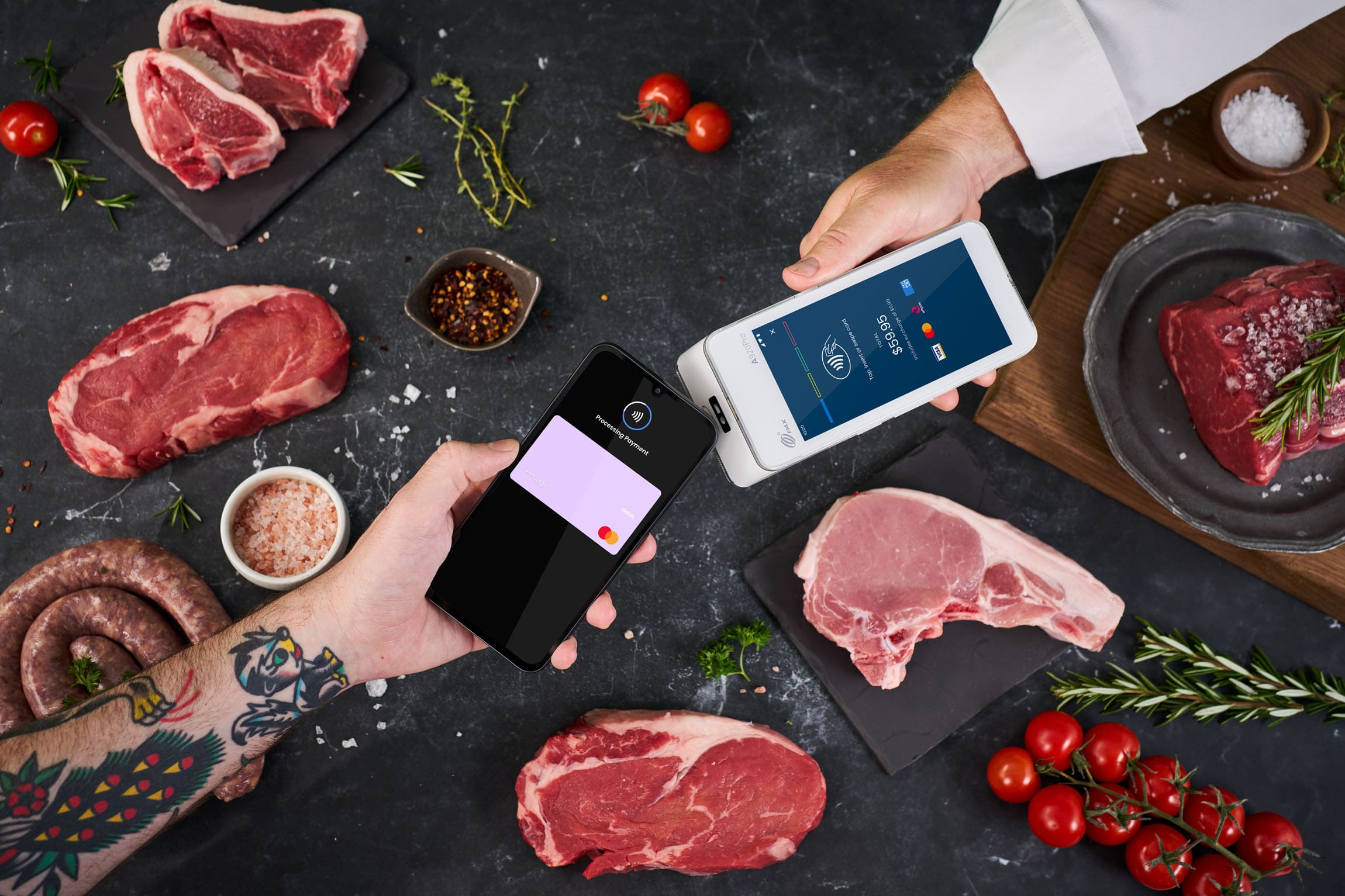 Phone tapping Android terminal to make payment, surrounded by assorted butcher meats